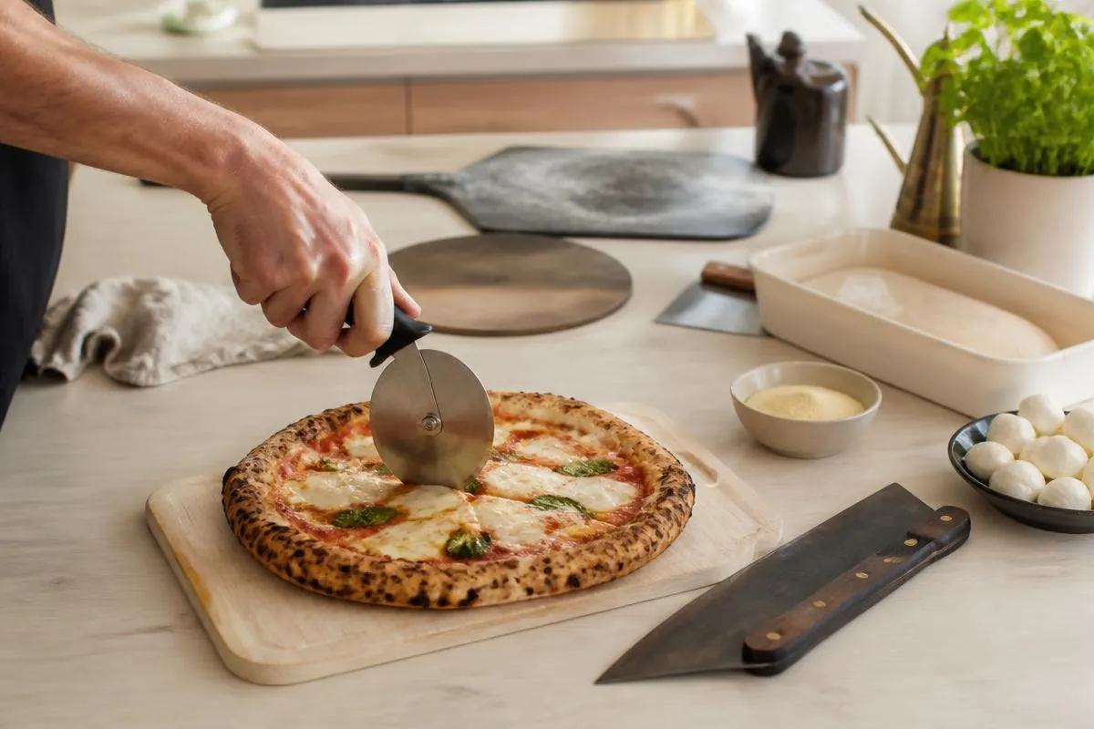 Et pizzahjul køres gennem en færdigbagt pizza med hånden på håndtaget